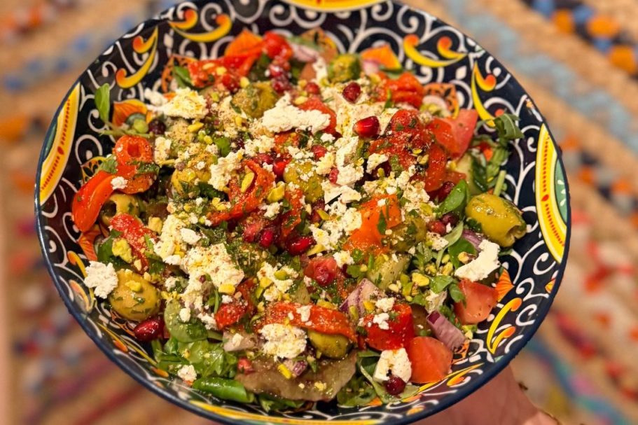 Een bord met salade en twee bastilla's, naast een Marokkaanse theepot en baghrir.