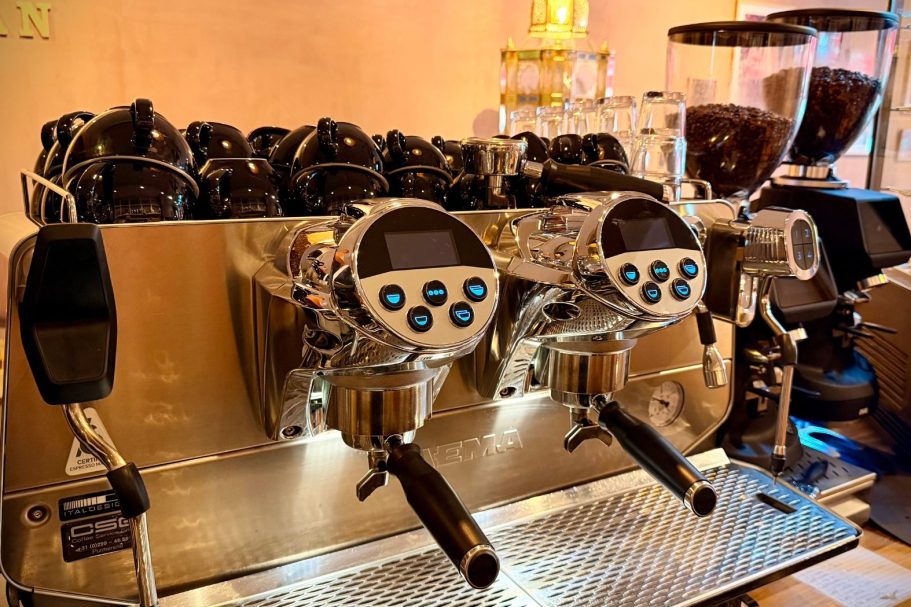 Professionele espressomachines met verlichte knoppen in een koffiebar.